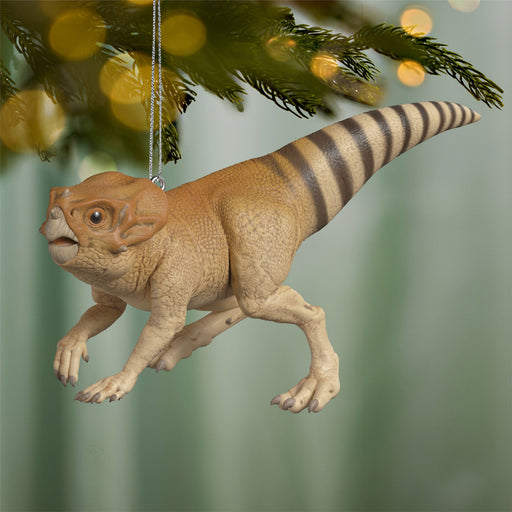 Dinosaur Christmas ornament hanging on a tree with blurred lights in the background