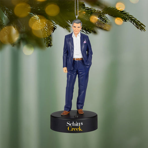 Ornament of a man in a blue suit hanging on a Christmas tree branch.