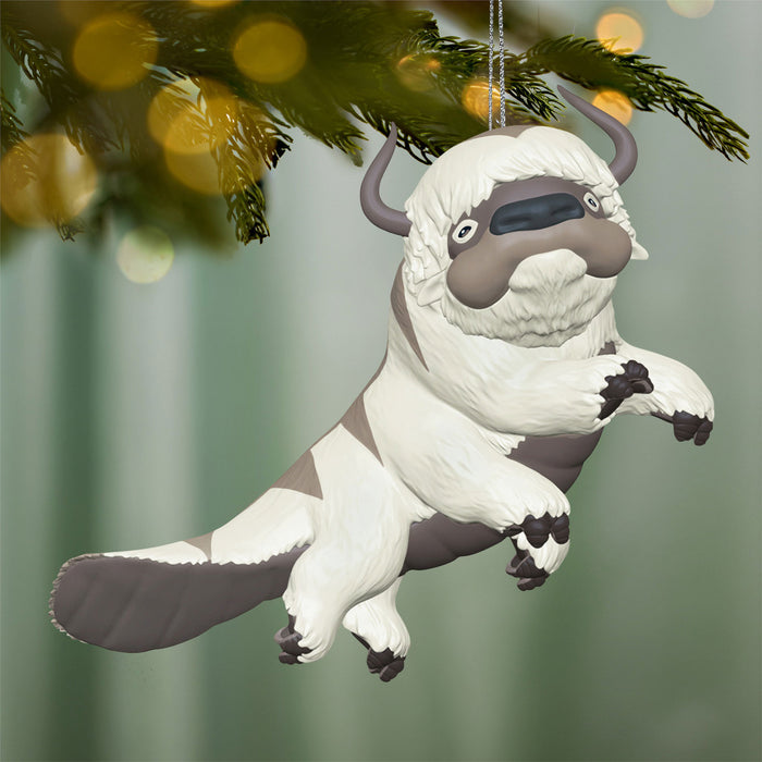 Anime creat ornament hanging on a Christmas tree with blurred lights in the background 