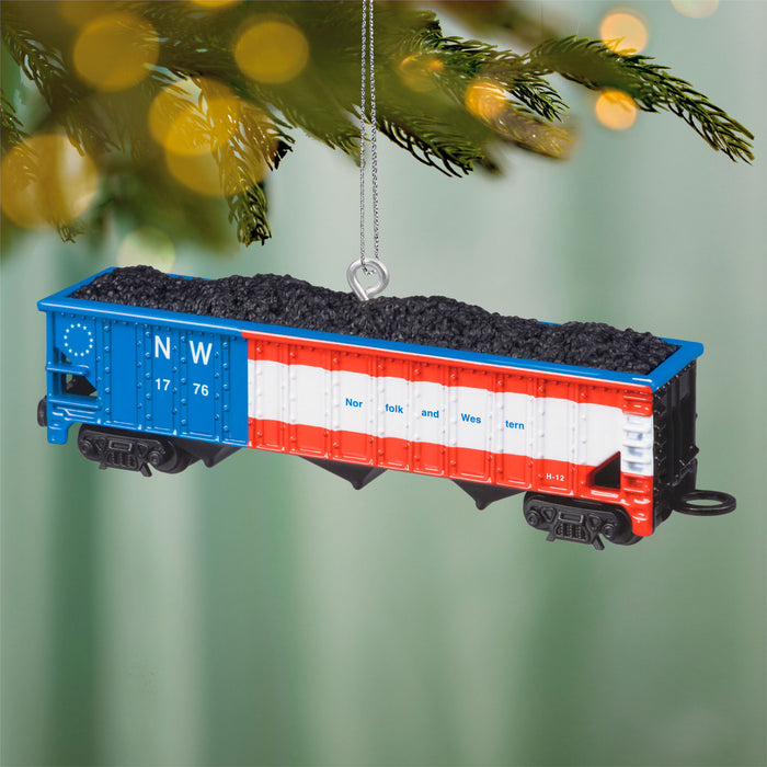 Decorative train car ornament with 'NW' branding hanging on a Christmas tree.