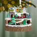 Christmas ornament with a train station, houses, and trees on a snowy landscape.