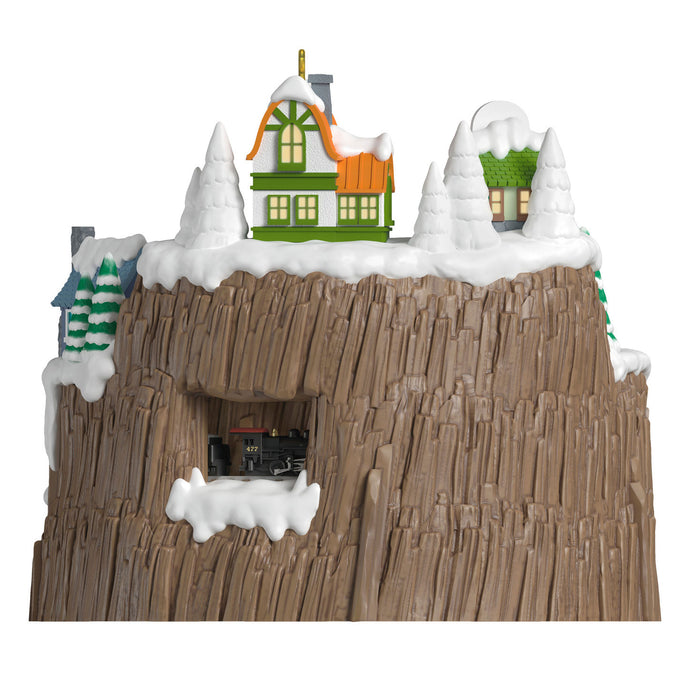 Toy train set on a wooden track with snow-covered houses and trees.