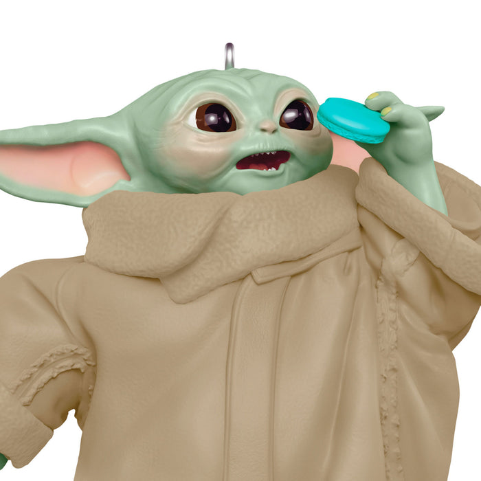 Baby Yoda figurine from 'The Mandalorian' holding a blue cup on a white background