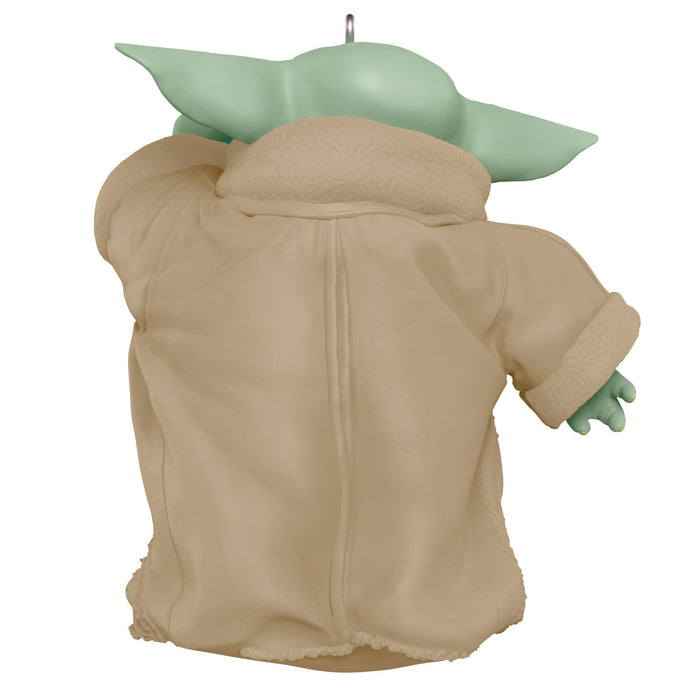 Baby Yoda figure with green head and beige body on a white background