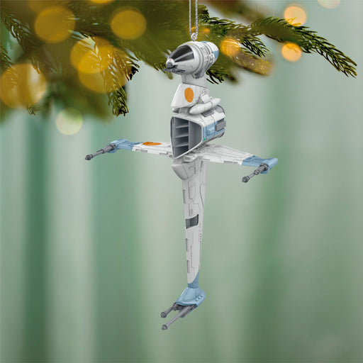 Star Wars X-wing fighter model ornament hanging on a Christmas tree.