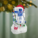 Christmas ornament resembling R2-D2 from Star Wars, decorated with lights and presents, against a blurred green background.