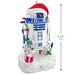 Christmas ornament of R2-D2 from Star Wars with Santa hat, lights, and gift, with a measurement label.