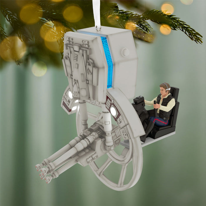 Ornament resembling a spaceship with a figure inside, hanging on a Christmas tree.