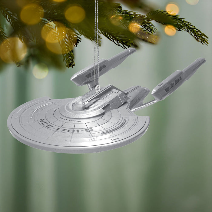 Star Trek ship ornament hanging on a Christmas tree with a blurred green background