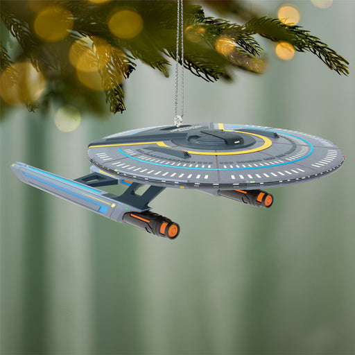 Star Trek ship ornament hanging on a Christmas tree with a blurred green background