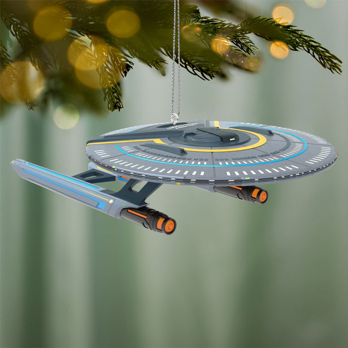 Star Trek ship ornament hanging on a Christmas tree with a blurred green background