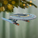 Star Trek ship ornament hanging on a Christmas tree with a blurred green background