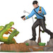 Figure of a character in a blue shirt with a weapon, standing next to a snake on a white background
