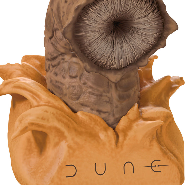 Close-up of a character head with a textured face and 'Dune' branding on a white background
