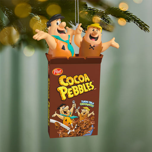 Cocoa Pebbles cereal box ornament with cartoon characters on a Christmas tree.