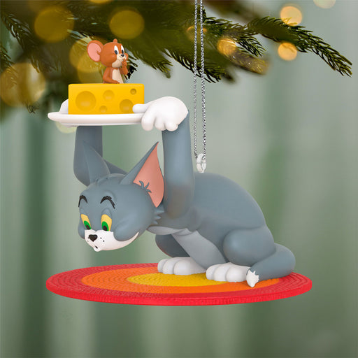 Animated cat character ornament holding cheese on a tree branch with blurred lights in the background