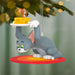 Animated cat character ornament holding cheese on a tree branch with blurred lights in the background
