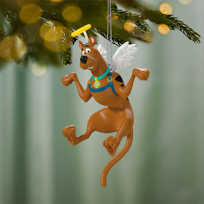 Scooby-Doo angel Christmas ornament hanging on a tree branch with blurred lights in the background.