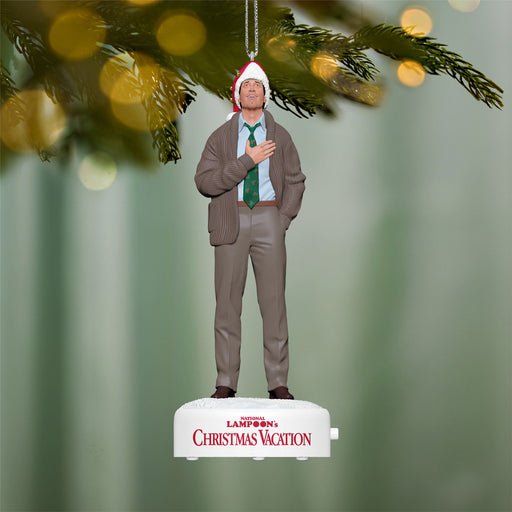 Christmas ornament of a man in a suit with a Santa hat, hanging from a tree branch.