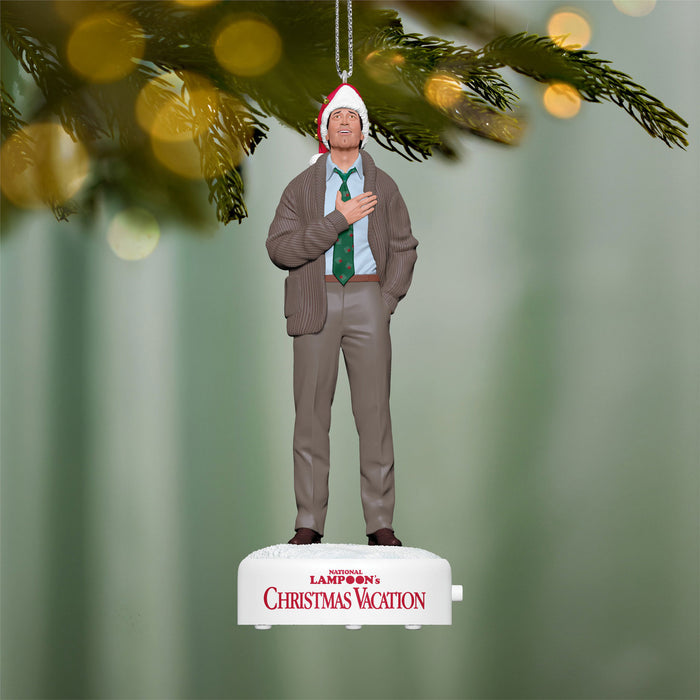 Christmas ornament of a man in a suit with a Santa hat, hanging from a tree branch.