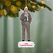 Christmas ornament of a man in a suit with a Santa hat, hanging from a tree branch.