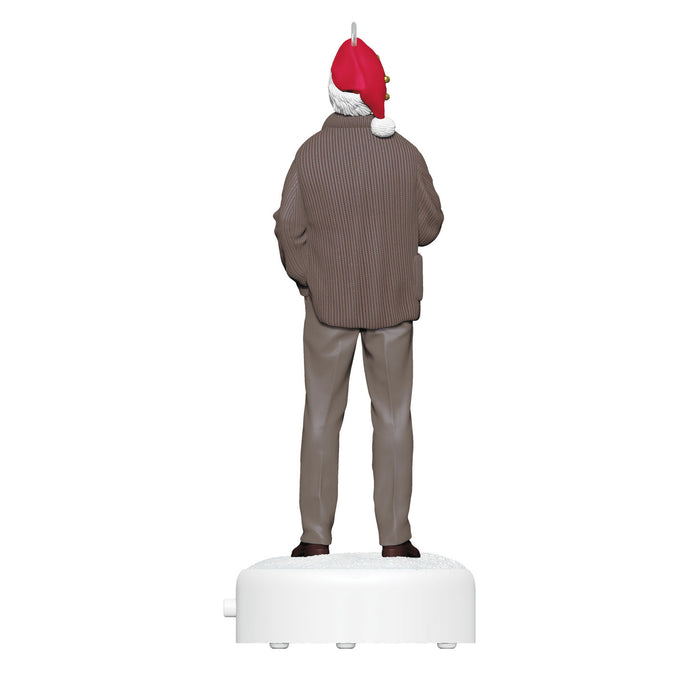Statue of a person wearing a brown sweater and gray pants with a red and white hat on a white base.