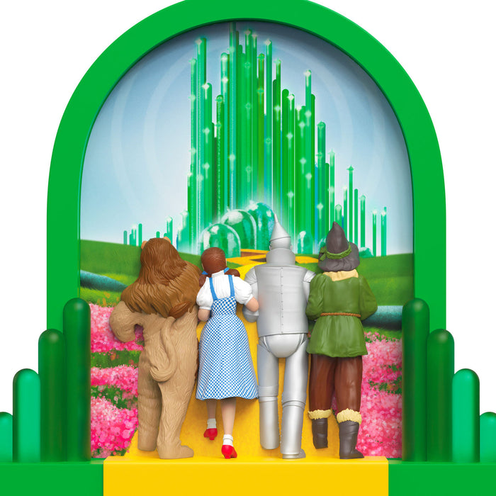 Toy figures of the Wizard of Oz characters in front of a green curtain with a wizard's hat.