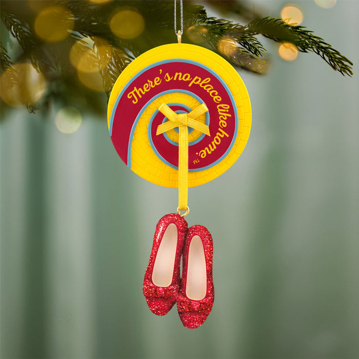 Decorative ornament with red shoes and yellow circle with text, hanging on a tree.