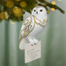 Decorative owl ornament with gold accents hanging on a tree branch.