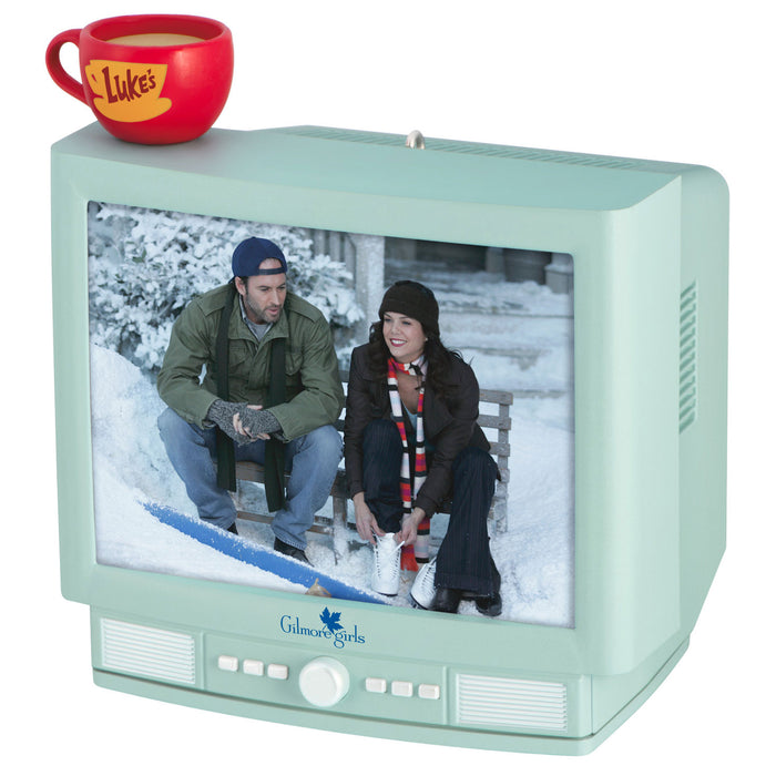 Small vintage-style TV displaying a scene from 'Gilmore Girls' with a red mug on top.