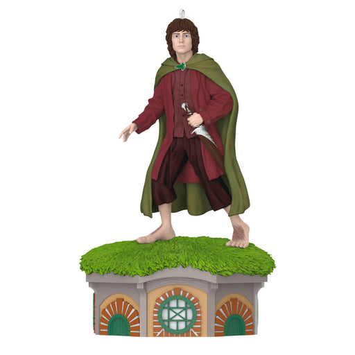 Figure of a character in a green cloak and red robe standing on a grassy platform with architectural elements.