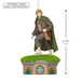Figurine of a character with a green cloak and brown bag on a small house-like platform, with dimensions indicated.