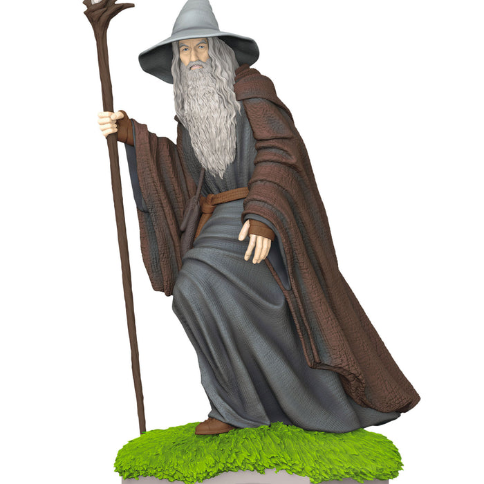 Statue of a character with a long beard, gray hat, and brown cloak holding a staff on a white background.