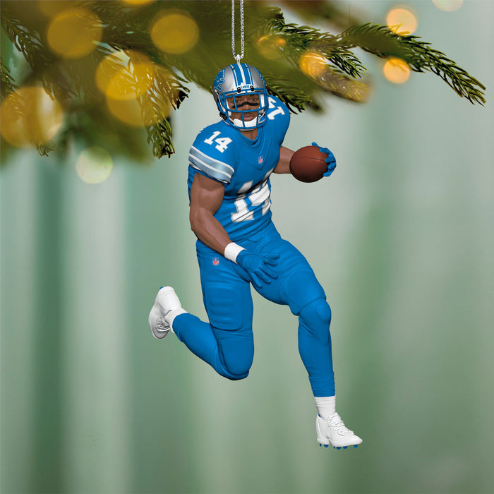 Decorative football player ornament in blue uniform with number 14 hanging from a tree.