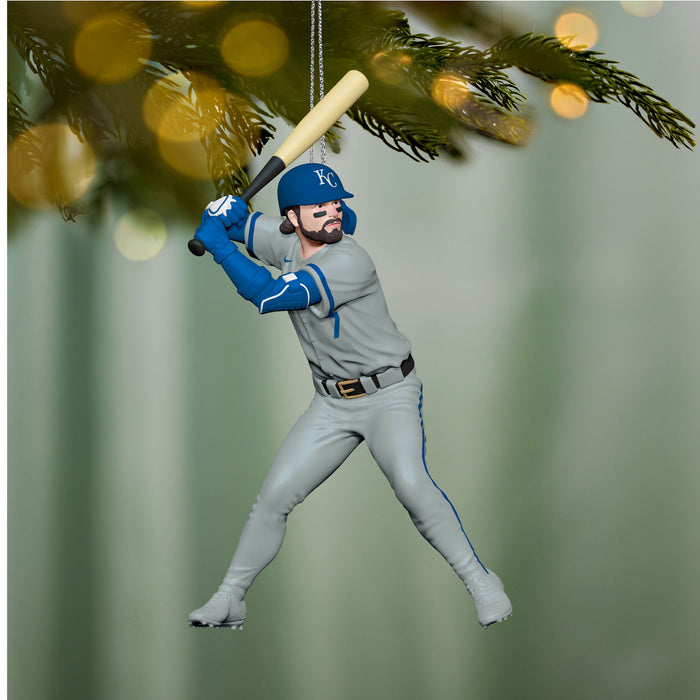 Baseball player ornament in a gray uniform with a blue helmet, holding a bat, hanging from a Christmas tree.