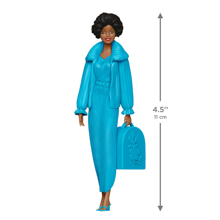 Toy figure of a woman in a blue outfit with a suitcase, showing height measurement.