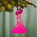 Decorative ornament of a woman in a pink dress with skull design, hanging from a tree.