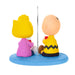 Two cartoon characters, one in yellow and pink and the other in yellow with a black zigzag pattern, sitting under an umbrella on a blue base.