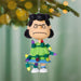 Christmas ornament of a character with green lights draped over them, hanging on a tree.