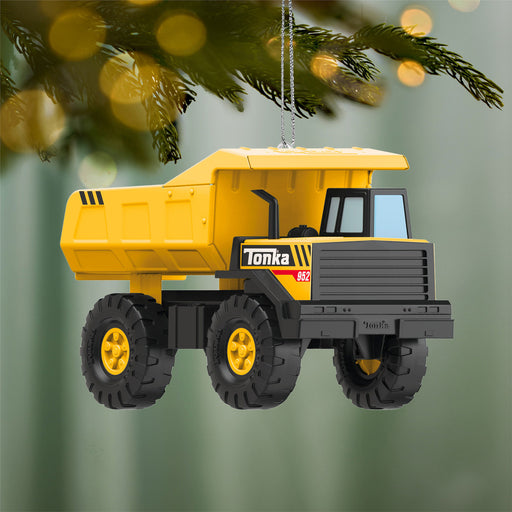 Yellow Tonka dump truck ornament hanging on a Christmas tree.