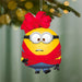 Minion character Christmas ornament with red bow on a blurred green background