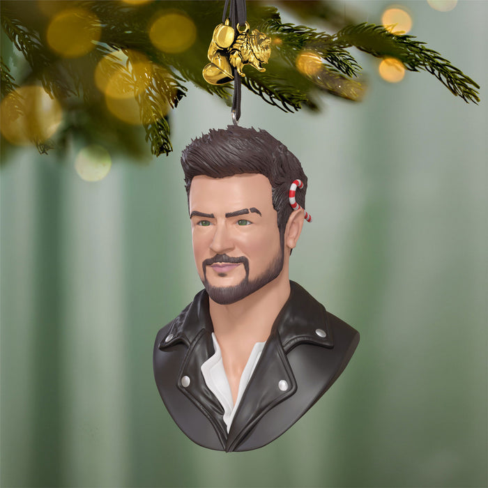 Decorative ornament shaped like a person's head with a beard, wearing a leather jacket, hanging from a Christmas tree.