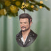 Decorative ornament shaped like a person's head with a beard, wearing a leather jacket, hanging from a Christmas tree.