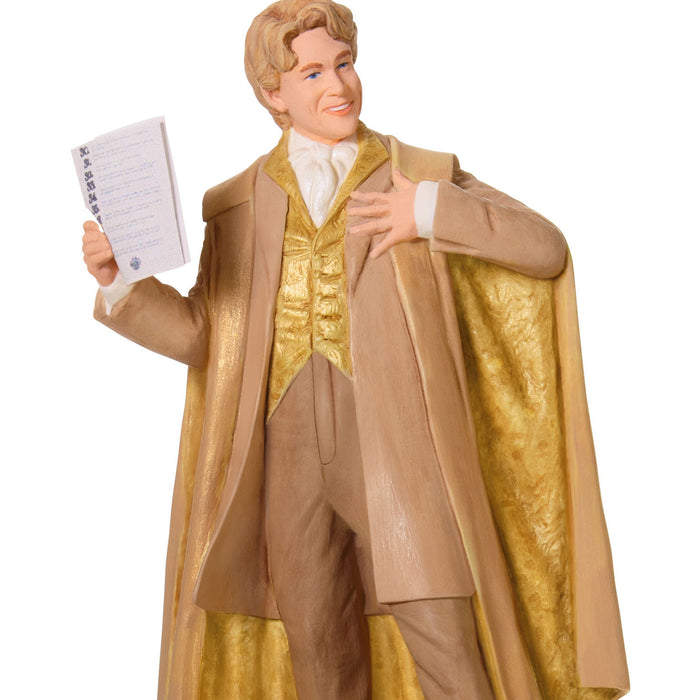 Figurine of a man in a beige coat and gold vest holding a sheet of music on a white background