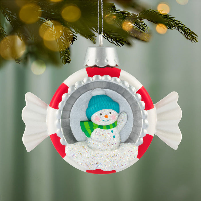 Christmas ornament with a snowman design on a blurred Christmas tree background