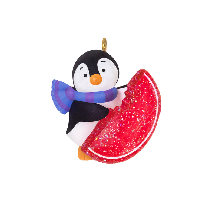 Penguin ornament with a red glittery candy on a white background