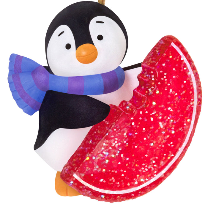 Penguin ornament with a red candy wedge and colorful scarf on a white background