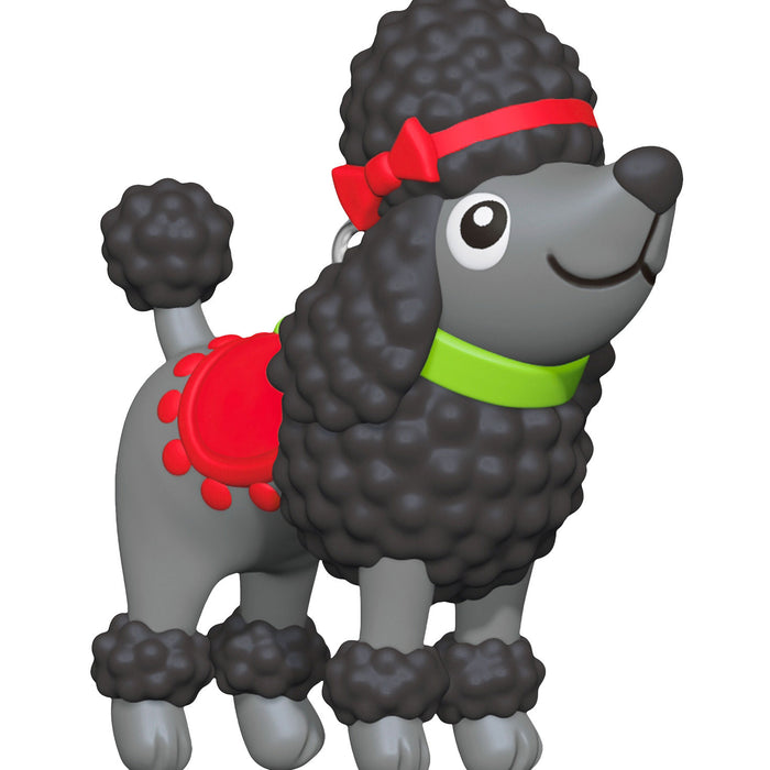 Toy poodle figure with a red bow and green collar on a white background