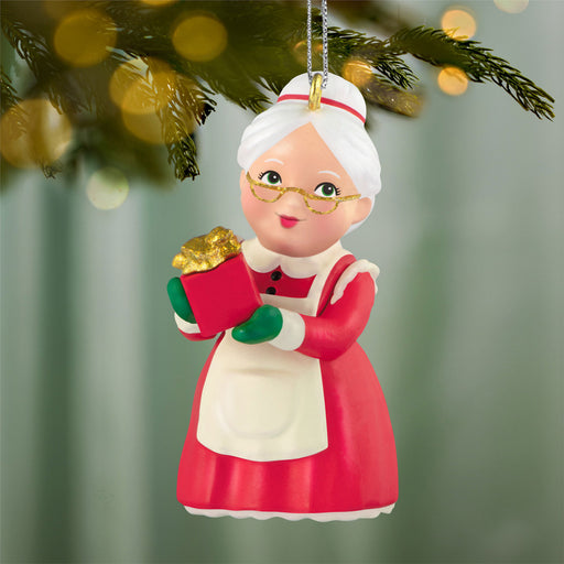 Christmas ornament of a character in a red dress holding a gift box, hanging from a tree.