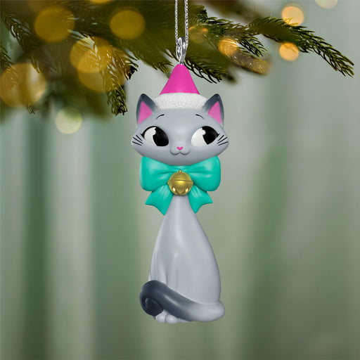 Cat-shaped Christmas ornament with a pink hat and green bow hanging on a tree.